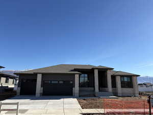Prairie-style house featuring a mountain view, a shingled roof, concrete driveway, and a garage