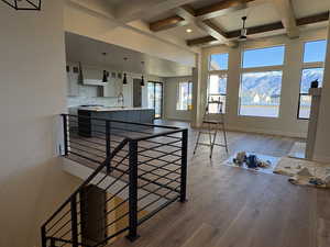 Kitchen with white cabinetry, beam ceiling, glass insert cabinets, decorative backsplash, and light countertops