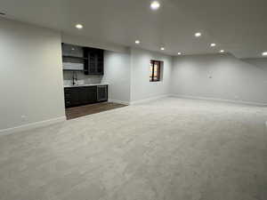 Indoor wet bar featuring open shelves, recessed lighting, dark cabinets, dark carpet, and beverage cooler