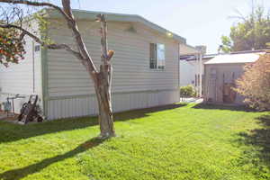 View of property exterior with a yard and a storage unit