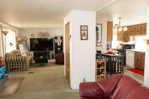 Living area with plenty of natural light, a chandelier, light colored carpet, and wallpapered walls