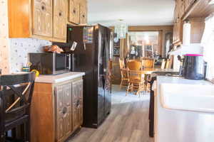 Kitchen with light countertops, wallpapered walls, and LVP floors