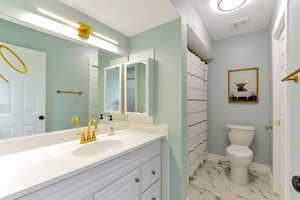 Full bath with curtained shower, vanity, and light marble finish flooring