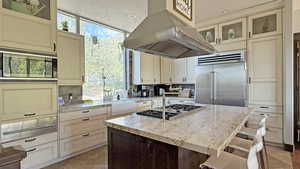 Kitchen featuring glass insert cabinets, light stone counters, a kitchen island, backsplash, and plenty of natural light