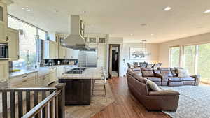 Kitchen with glass insert cabinets, island exhaust hood, a breakfast bar area, light stone countertops, and light wood-style flooring