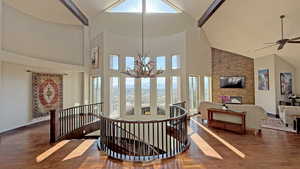 Stairway with wood finished floors, high vaulted ceiling, a chandelier, and beamed ceiling