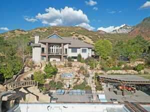 Rear view of house featuring a chimney, a patio, a mountain view, and an empty pool
