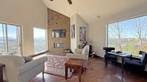 Living area featuring high vaulted ceiling, a fireplace, hardwood / wood-style flooring, a ceiling fan, and a mountain view