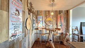 Bar featuring wood walls, dark wood-style floors, a textured ceiling, and pendant lighting
