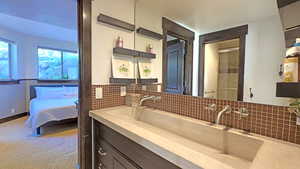 Full bathroom with double vanity, backsplash, and ensuite bathroom