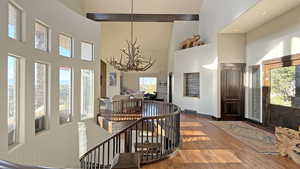 Foyer featuring wood-type flooring, a towering ceiling, and a chandelier