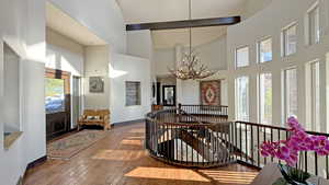 Entrance foyer featuring wood-type flooring, a chandelier, a high ceiling, and beamed ceiling