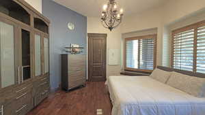 Bedroom with dark wood finished floors and a chandelier