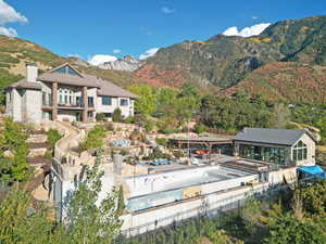 Rear view of property with a mountain view, a chimney, a balcony, stone siding, and a patio area