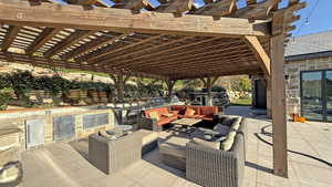 View of patio featuring a pergola, an outdoor hangout area, and an outdoor kitchen