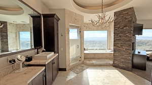 Bathroom featuring a raised ceiling, a garden tub, vanity, a shower stall, and plenty of natural light