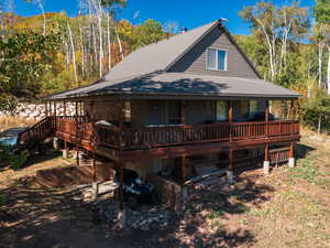 Back of house featuring covered porch, a metal roof, and a view of trees