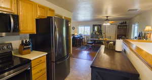 Kitchen featuring appliances with stainless steel finishes, light countertops, brown cabinets, and a ceiling fan