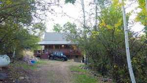 View of front of home featuring a deck, a metal roof, and driveway