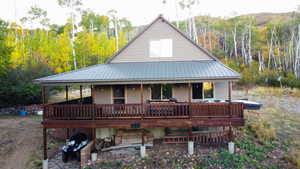 View of front facade with a metal roof and a view of trees