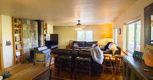 Living area with a wood stove, a ceiling fan, dark wood-style flooring, and built in features
