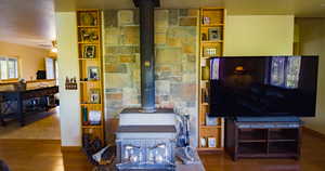 Living area featuring a wood stove, wood finished floors, a textured ceiling, and ceiling fan