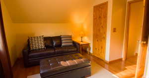 Guest room with lofted ceiling and wood finished floors fold out couch.
