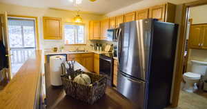 Kitchen with stainless steel appliances, light countertops, hanging light fixtures, ceiling fan, and dark tile patterned floors