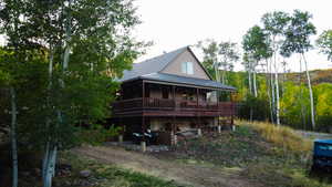 Rear view of house featuring a metal roof, a forest view, and a large porch