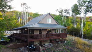 View of front of house featuring a porch, a metal roof, and a forest view