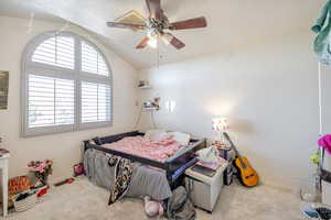 Carpeted bedroom featuring lofted ceiling, a textured ceiling, and ceiling fan