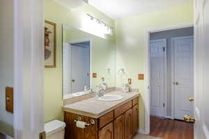 Bathroom with a textured ceiling, vanity, and light wood-style flooring