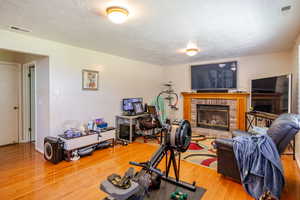 Living room featuring a textured ceiling, a fireplace, and light wood-style flooring
