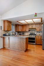 Kitchen with backsplash, brown cabinets, and light wood finished floors