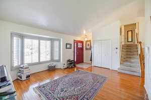 Foyer with light wood-style floors, vaulted ceiling, and stairway