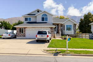 View of front of home featuring a mountain view, driveway, brick siding, an attached garage, and a shingled roof