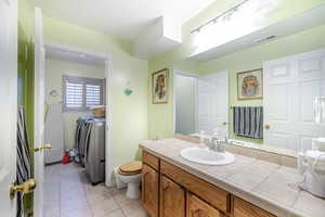 Bathroom featuring light tile patterned floors, vanity, and independent washer and dryer