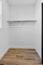 Walk in closet with light wood finished floors