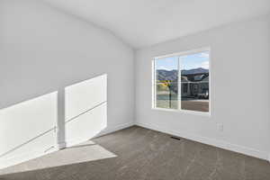 Carpeted spare room with lofted ceiling and baseboards