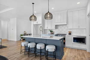 Kitchen featuring white cabinets, decorative backsplash, stainless steel appliances, recessed lighting, and light wood-type flooring