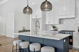 Kitchen with light wood-style floors, white cabinetry, gas stove, and recessed lighting