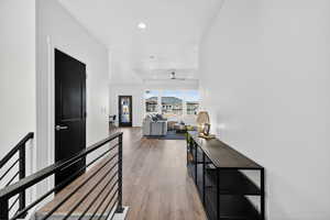 Hallway with light wood-type flooring, an upstairs landing, and recessed lighting