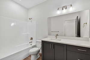 Bathroom with vanity, shower / bath combination, and dark wood-style flooring