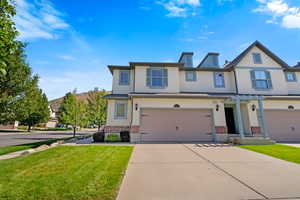 View of front facade featuring brick siding, stucco siding, a front lawn, driveway, and an attached garage