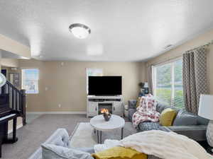 Carpeted living area with a textured ceiling and baseboards