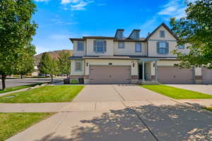 Traditional home with brick siding, a front yard, concrete driveway, and stucco siding