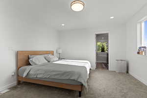 Carpeted bedroom with connected bathroom and recessed lighting
