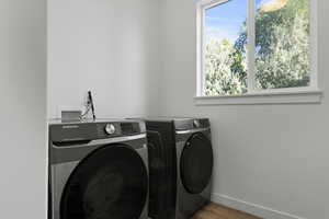 Laundry room featuring plenty of natural light, wood finished floors, and independent washer and dryer
