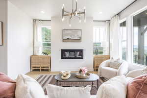 Living room with a glass covered fireplace, wood finished floors, a chandelier, and recessed lighting