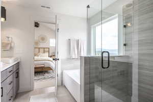 Ensuite bathroom featuring a bath, vanity, light tile patterned floors, and a stall shower